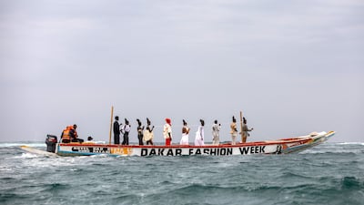 Models stand on a pirogue as they present the creations of African designers, during Dakar Fashion Week in Senegal. EPA