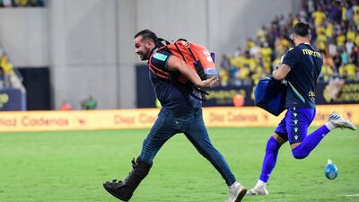 An emergency service member runs on the pitch carrying medical equipment during a play interruption after a supporter collapsed in the stands. AFP