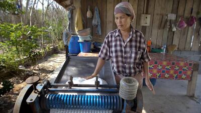 Slabs of rubber are fed through a press to flatten it for drying. Paula Bronstein / Getty Images