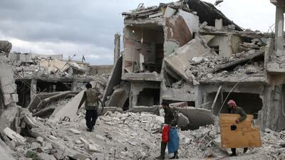 People walk on rubble of damaged buildings in the besieged town of Douma, Eastern Ghouta. Reuters, file