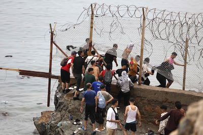 A crowd of men breaking through a fence at Morocco's border with the Spanish enclave of Ceuta. AFP