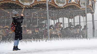 A woman takes pictures during a snow storm at Brooklyn Bridge Park on March 21, 2018 in New York City. AFP