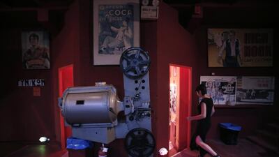 A moviegoer walks past an old projector on display at the entrance of the Zefyros vintage-movie cinema in Ano Petralona, near central Athens.