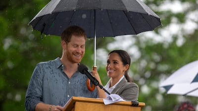 Meghan holds an umbrella for Prince Harry as he addresses the public during a Community Event in Dubbo, Australia, in October 2018. Getty Images