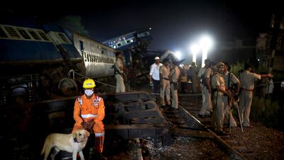 A man from National Disaster Response Force (NDRF) takes a break from rescue operations next to the upturned coaches of the Kalinga-Utkal Express. Altaf Qadri / The Associated Press