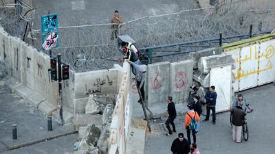 Anti-government protesters climb a concrete wall installed by authorities to keep protesters far from the main Lebanese government headquarters and open road to parliament, in downtown Beirut, Lebanon. AP Photo