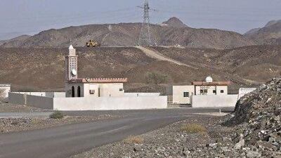 Workers in the distance add an arm carrying electricity transmission lines to this transmission tower in Lahzoom, Ras al Khaimah. Jeff Topping / The National