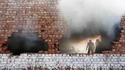 Firefighters try to douse a blaze at a footwear factory in New Delhi. Adnan Abidi / Reuters