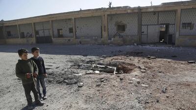 Boys stand at a ground damaged by what activists said were air strikes carried out yesterday by the Russian air force at a school in Jerjnaz town in Idlib province, Syria. Khalil Ashawi / Reuters