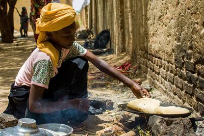 A girl prepares food outside at a camp for the internally displaced in Al Suwar, about 15 kilometres north of the Sudanese city of Wad Madani. AFP
