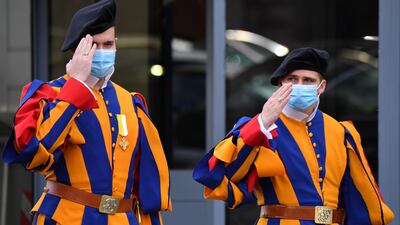 Swiss Guards wearing a face mask give a salute as they stand guard at an entrance of The Vatican. AFP