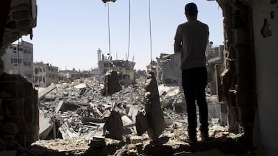 A Palestinian stands in a damaged window against the massive destruction of a homes reduced to rubble from the fighting between Israeli military forces and Palestinian fighters in the Gaza Strip during a humanitarian truce on Saturday. Photo by Heidi Levine for The National