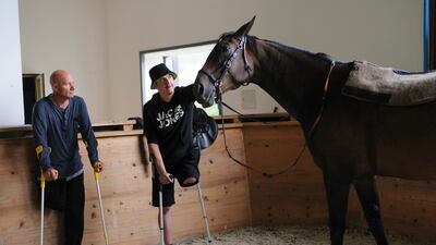 Wounded Ukrainian soldiers Yury (L) and Vasyl pet a horse during their course of therapy near the western Ukrainian city of Lviv. EPA