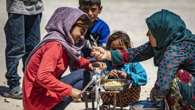 A displaced Syrian girl grinds a customer's chickpeas for a fee, during Ramadan, at the Washukanni camp for the internally displaced in Syria's northeastern Hasakeh province. AFP