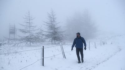 A man walks alongside Brun Clough Reservoir in snowy and foggy conditions above the village of Delph, near Manchester. AFP
