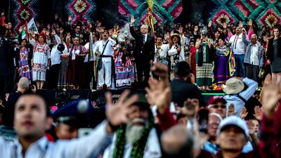 Andres Manuel Lopez Obrador and attendees raise their arms. Bloomberg