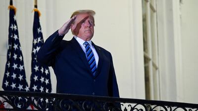 US President Donald Trump salutes as he poses without a face mask on the Truman Balcony of the White House after returning from being hospitalised. Reuters