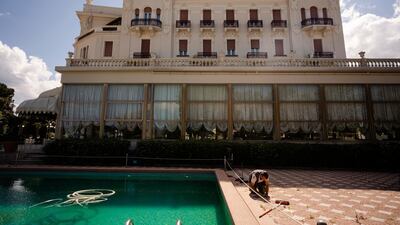 A man does maintenance work by a swimming pool of the Rimini Grand Hotel, in Rimini, Italy. The seaside resort is gearing up to welcome tourists again. AP Photo/Domenico Stinellis