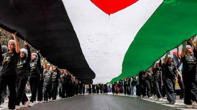 People march with a giant Palestinian flag during a demonstration commemorating the Nakba's 78th anniversary in Ramallah. AFP