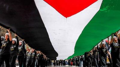 People march with a giant Palestinian flag during a demonstration commemorating the Nakba's 78th anniversary in Ramallah. AFP