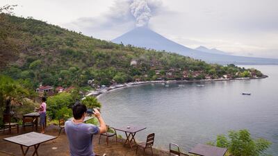 A tourist takes a photo of Mount Agung spewing volcanic ash from the popular Sunset Point in Amed on November 28, 2017 in Karangasem, Island of Bali, Indonesia. Andri Tambunan / Getty Images