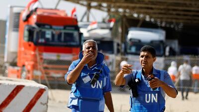 UN workers gesture as lorries carrying aid arrive at the Palestinian side of the border with Egypt on October 21. Reuters