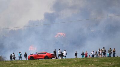 People watch as structures burn from a wildfire on Wednesday, March 30, 2022, in Sevierville, Tennessee, amid mandatory evacuations as winds whipped up beforea line of strong storms forecast to move in overnight. Knoxville News Sentinel / AP