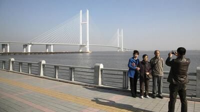 People pose for pictures with the new Friendship Bridge over the Yalu River, connecting China's Dandong and North Korea's Sinuiju, November 9, 2014. According to local media, the plan for opening the new Friendship Bridge in October was delayed and no new scheduled date has been released yet. Picture taken November 9, 2014. REUTERS/Jacky Chen (CHINA - Tags: SOCIETY BUSINESS CONSTRUCTION POLITICS)