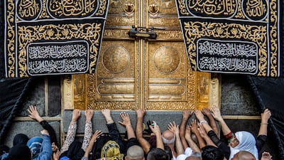 Muslim pilgrims reach up towards the golden doors of the Kaaba at the centre of the Grand Mosque in Makkah. AFP