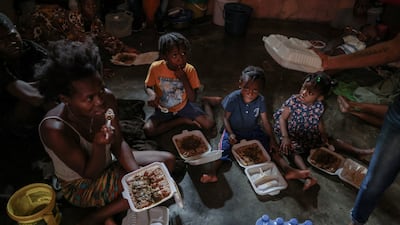 People displaced by gang war violence eat food distributed by a community action centre