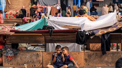 Children play on a phone in the playground of a school in Khan Younis, Gaza, run by the UN agency for Palestinian refugees. AFP