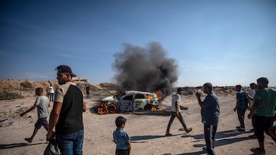 Palestinians gather near a burning vehicle after it was hit by an Israeli airstrike south of Gaza City. EPA