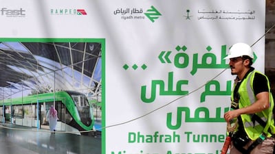 A worker walks past a poster at a metro construction site. AFP