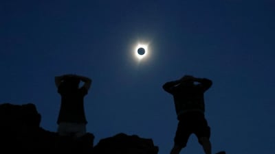 Enthusiasts Tanner Person, right, and Josh Blink, both from Vacaville, California, watch a total solar eclipse while standing atop Carroll Rim Trail at Painted Hills, a unit of the John Day Fossil Beds National Monument, near Mitchell, Oregon, US. Adrees Latif / Reuters