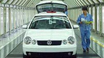 A worker walks past a Polo car at a production line in Shanghai Volkswagen Automotive Company. One out of every 120 Chinese now own their own car.
