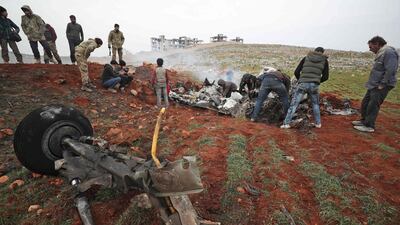 People search for scrapes of metal among the debris of a Syrian military helicopter that was shot down on February 14, 2020, in the western countryside of Aleppo province. AFP