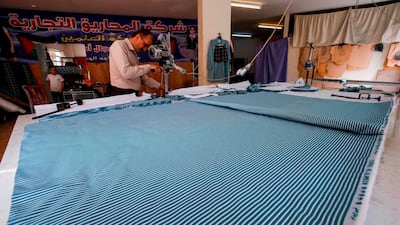 Palestinian workers cut cloth for the school uniforms they're creating. AFP