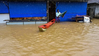 A man stands outside his home partially submerged in floodwater, on the outskirts of Colombo. AFP