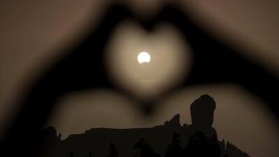 A woman makes a heart shape with her hands during a partial eclipse of the sun over the 'Roque Nublo' mountain at the Canary Island of Gran Canaria, Spain. Borja Suarez / Reuters