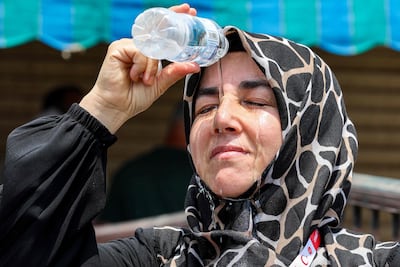 A departing Turkish pilgrim pours cold water on her head to cool off as she waits in Makkah. AFP