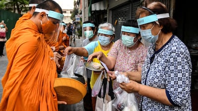 Buddhist monks wearing face shields and mask to protect themselves from the coronavirus disease (COVID-19) collect alms in Bangkok, Thailand. REUTERS