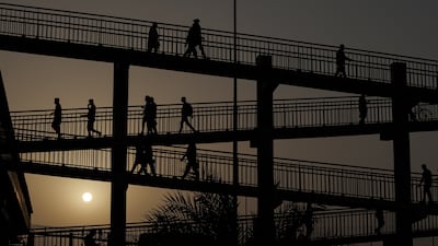 Workers cross a pedestrian bridge heading to Ras Al Khor fruit and vegetable market in Dubai. EPA