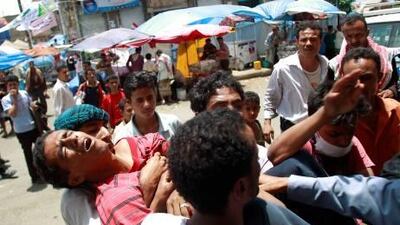 Anti-government protesters carry a wounded fellow demonstrator to hospital after clashes with police and army soldiers in the southern city of Taiz yesterday. Government forces fired machine guns the protest against Yemen's entrenched president, wounding dozens.