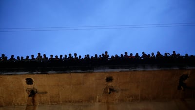 People stand on a bridge and watching Hindu devotees immerse the Hindu Goddess Durga into a river in Dhaka, Bangladesh. Abir Abdullah / EPA