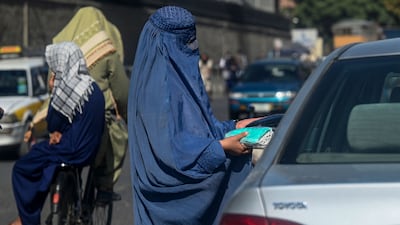 A burqa-clad woman sells face masks to commuters at a traffic intersection in Kabul. AFP