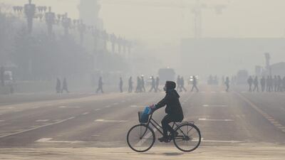 A woman wears a mask as she rides her bicycle along a street near Tiananmen Square in Beijing. AFP