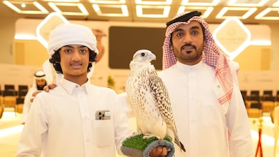 Salman Albalooshi from Bahrain with his son Hassan at the Adihex falcon auction on Sunday. Pawan Singh for The National