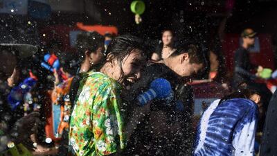 A woman reacts to being soaked in water during Songkran, or the Thai New Year, celebrations on Khaosan Road in Bangkok. Lillian Suwanrumpha / AFP