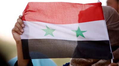 A woman holds a Syrian flag in Deraa, Syria, on July 4, 2018. Reuters