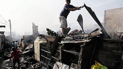 A Filipino tries to recover possessions from a fire in Manila that killed seven and left thousands homeless on Christmas Day.